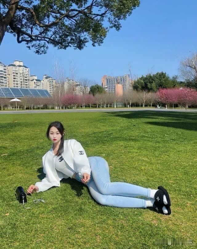 阳光明媚的午后，绿草如茵的公园，少女悠闲地躺在草地上，享受着宁静的时光。