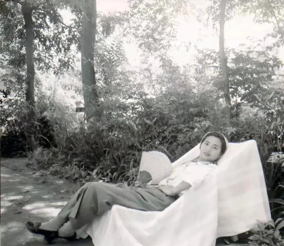 1956年，陈毅元帅夫人张茜手拿扇子，斜躺在树下椅子上休憩的老照片，阳光透过树叶