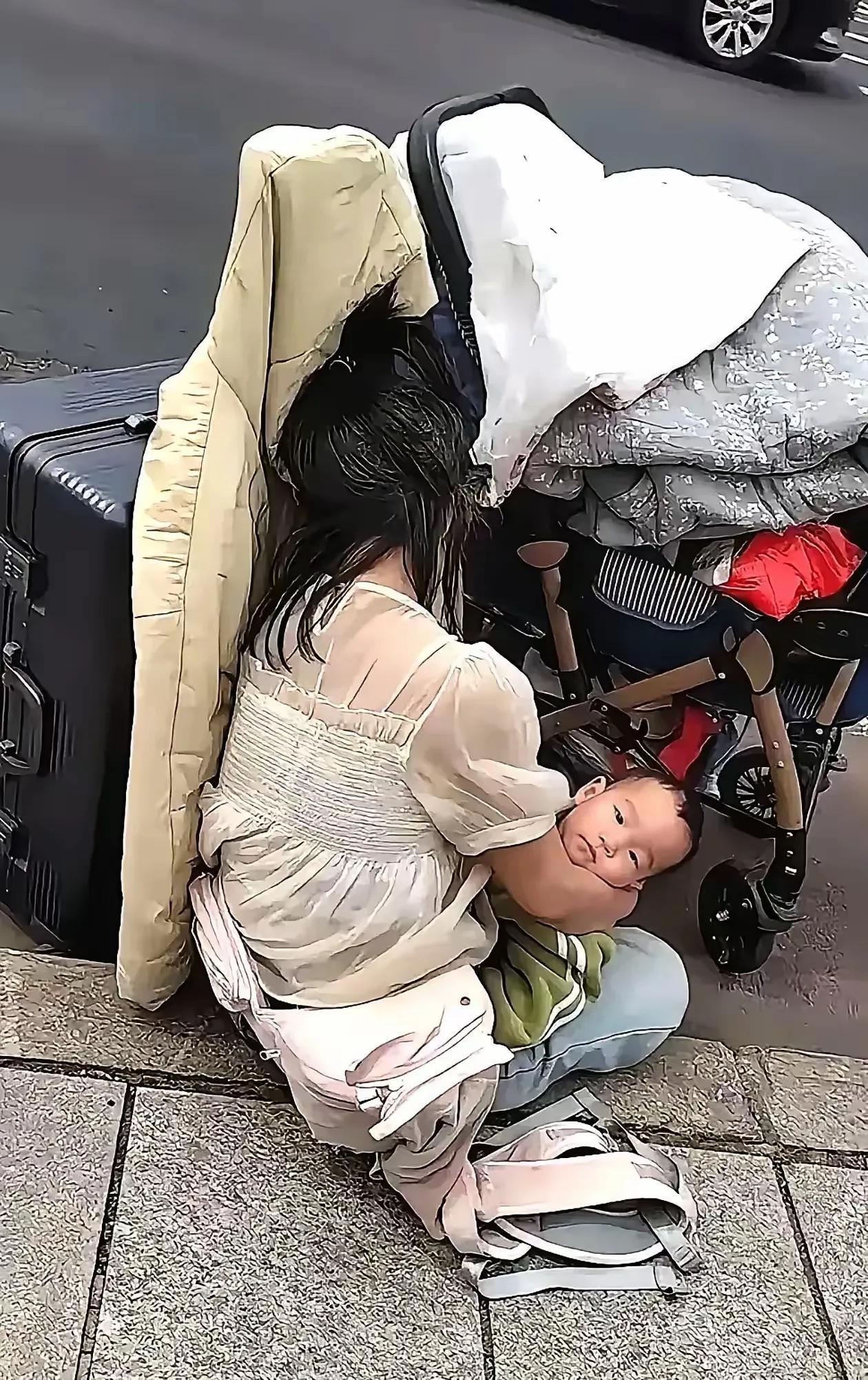 街上心酸的一幕在大街上，看到一个女子抱着几个月大的孩子，坐在地上，孩子已经睡着