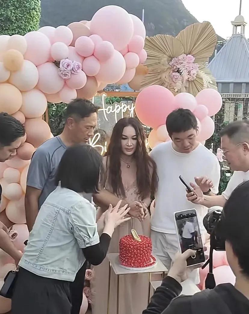 59岁温碧霞过生日时，身着粉色吊带、脚踩银色高跟，一头浓密长发搭配精致妆容，显得