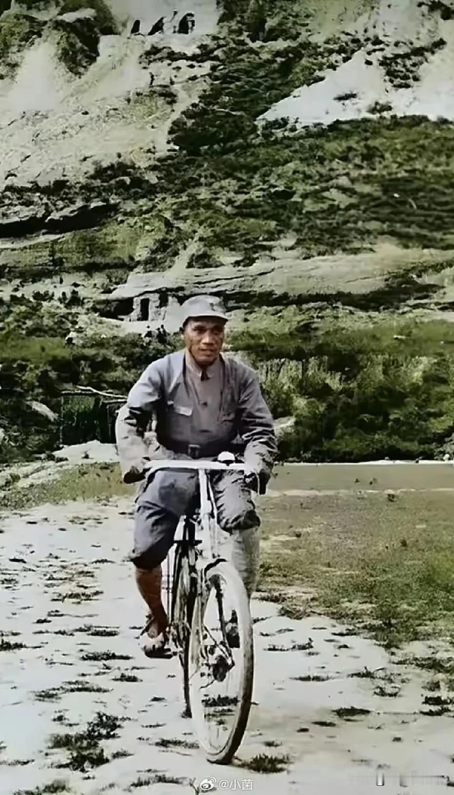 1938年延安，朱德总司令骑着老式自行车行进在山间土路。窑洞群山为伴，旧单车代步