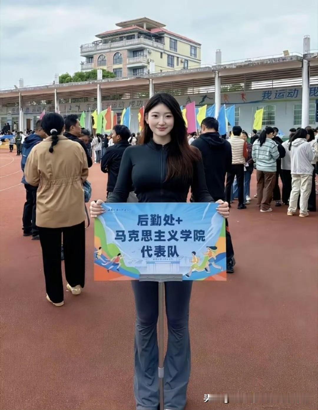 今天刷到一张照片，一个长发女生在操场举着牌子，上面写着“后勤处+马克思主义学院代