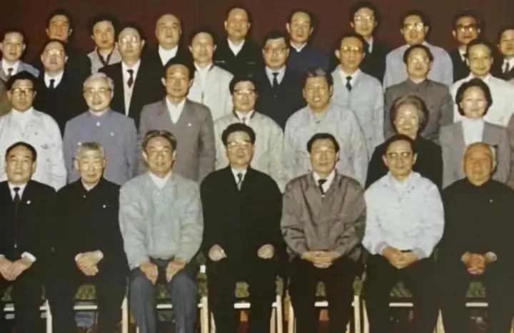 1990年，李鹏同志于上海视察期间与工作人员合影。照片中他身着黑色西装神情专注，