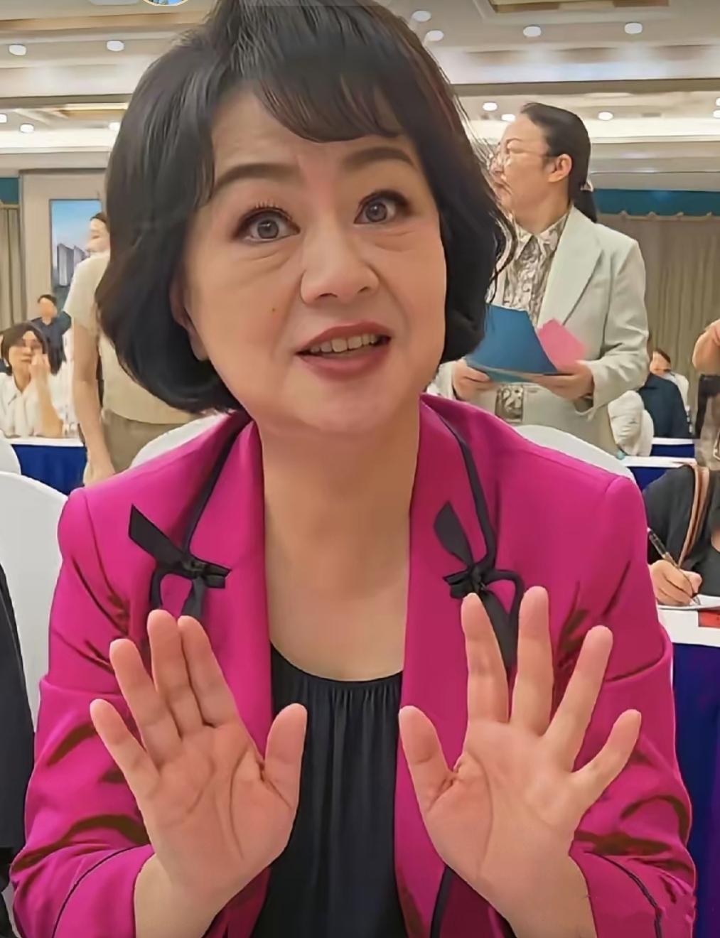 画面中穿着玫粉色上衣的鞠萍发型干练，张眉努眼，睫毛长翘，唇若丹霞，素齿如贝，略显