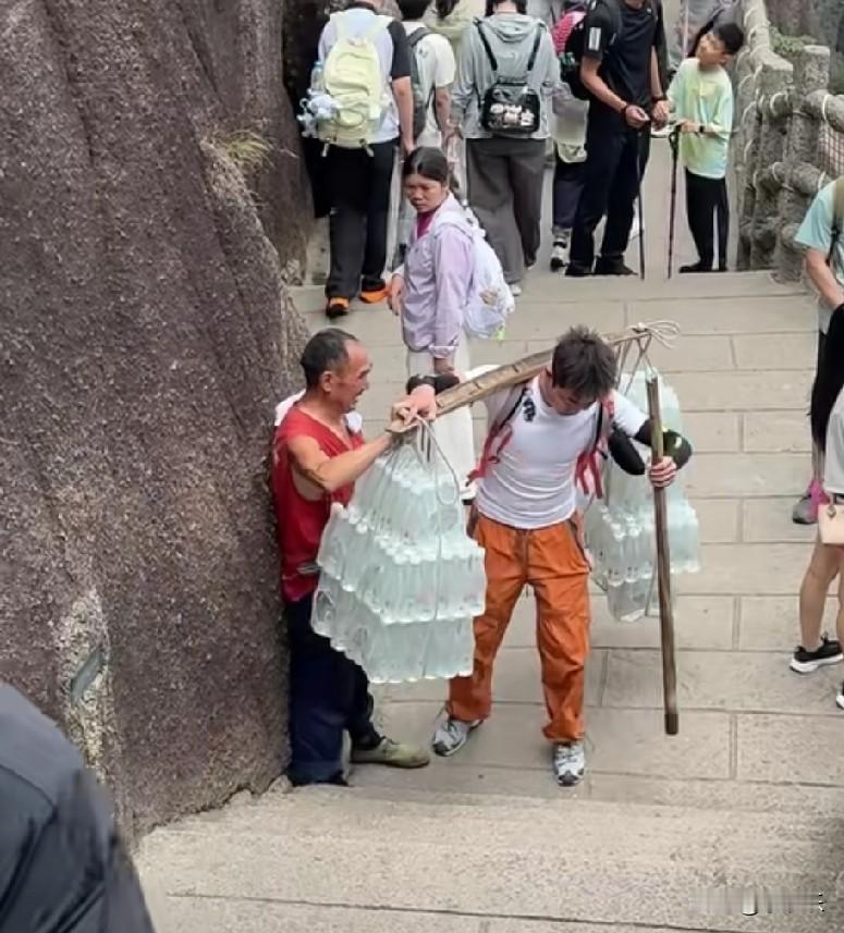 7月28日，安徽黄山，一90后小伙爬黄山途中，遇到一挑山工，扁担两头挑了满满的矿