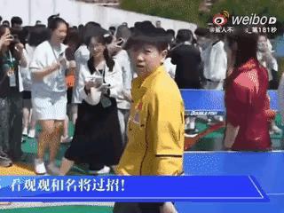 仔细看视频一，莎莎被晒得表情都变形了，一个短袖黑体恤黑裤子的女生速度很快地站在了