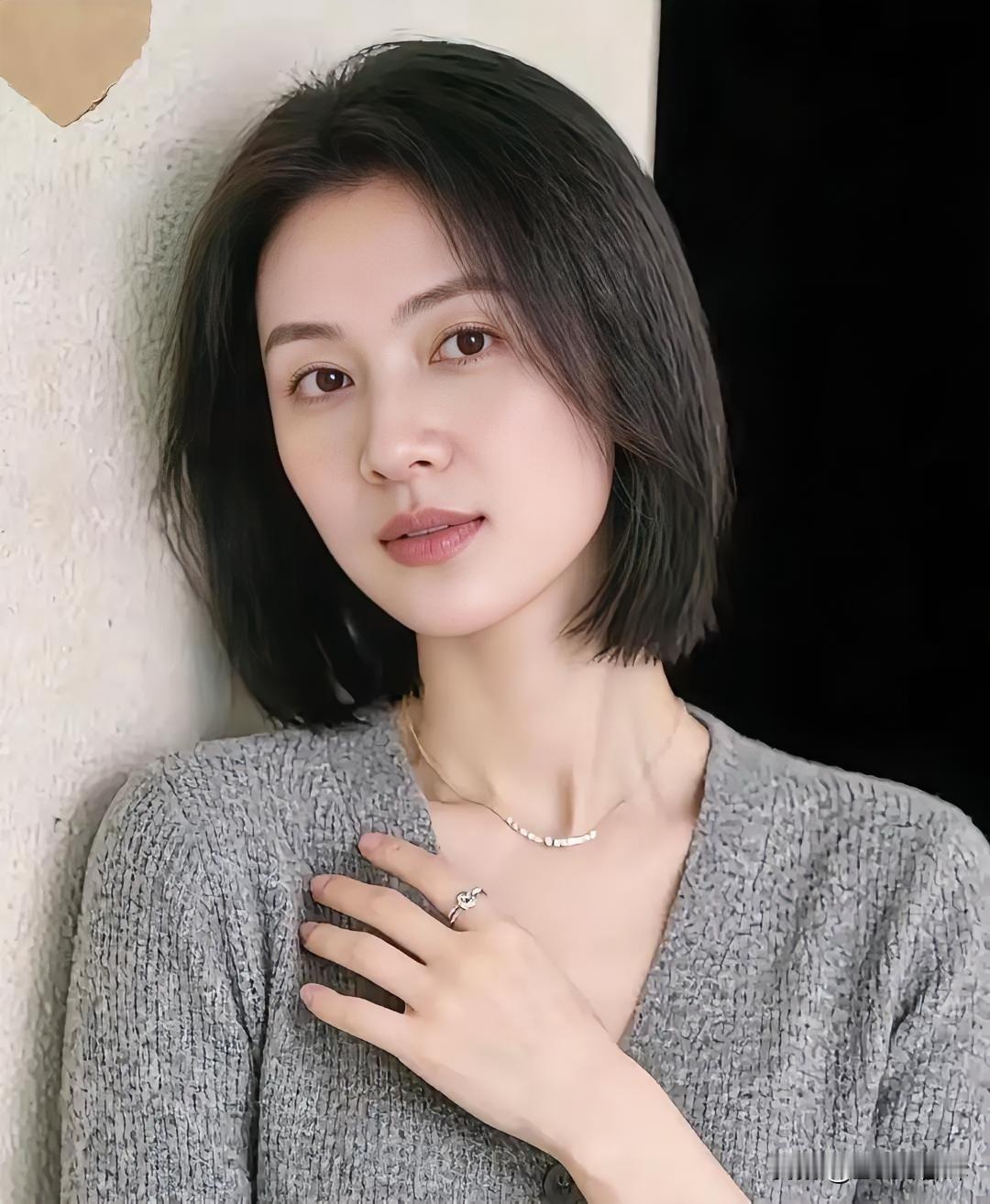 灰衣如雾，裹住时光的温柔肌理。短发齐整，衬出颈线的干净利落。她倚素墙，手