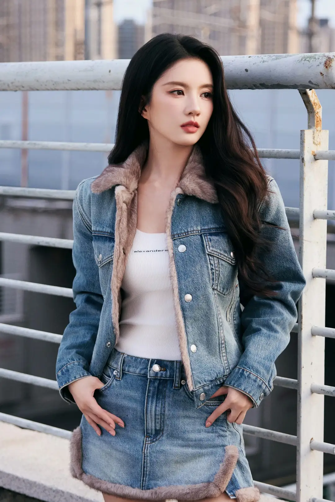 一个穿牛仔外套的女孩站在栏杆旁。(刘些宁)