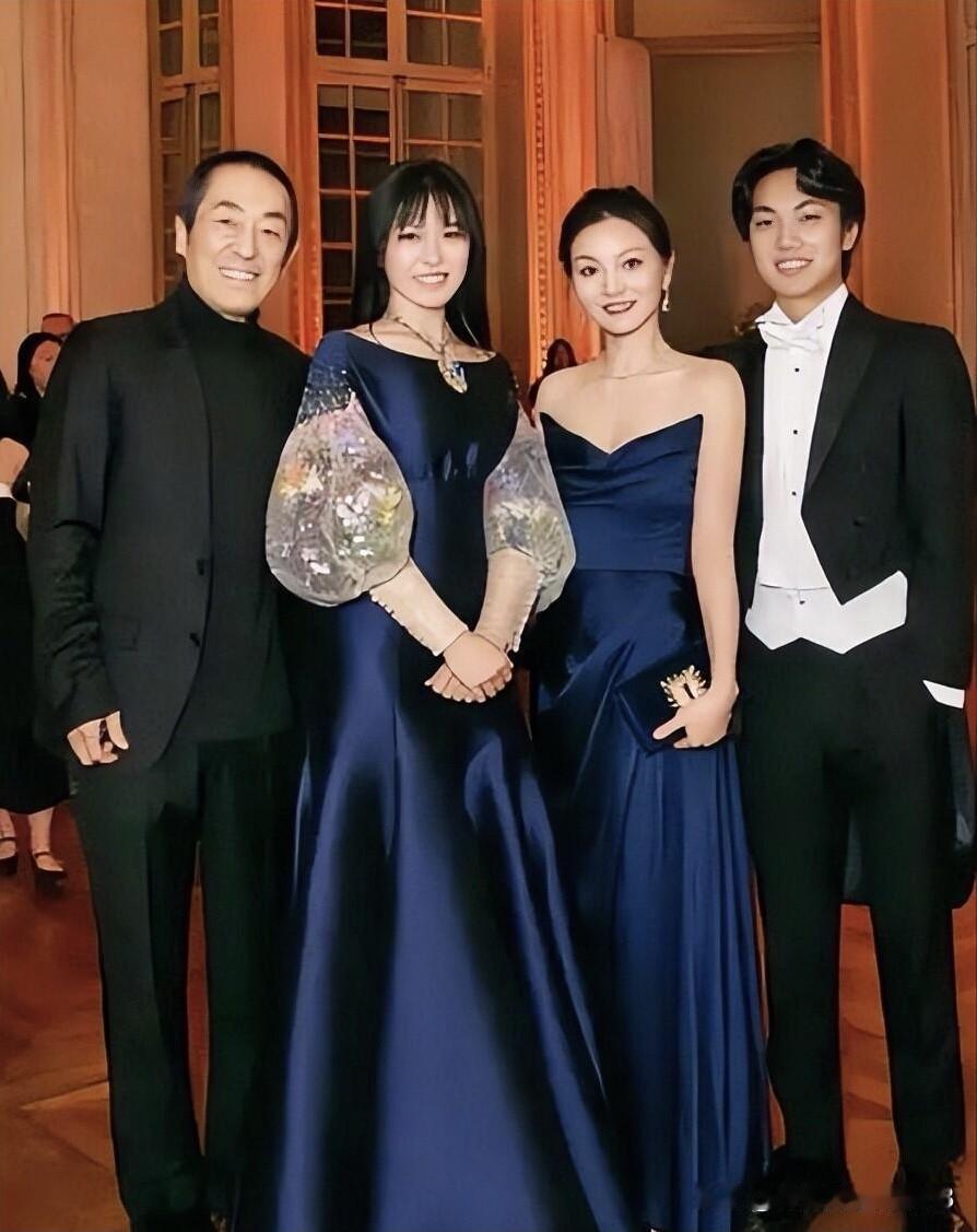 张艺谋一家四口的合影，女儿跟妈妈陈婷穿着同色系的礼服裙，身高比妈妈高，但颜值一般