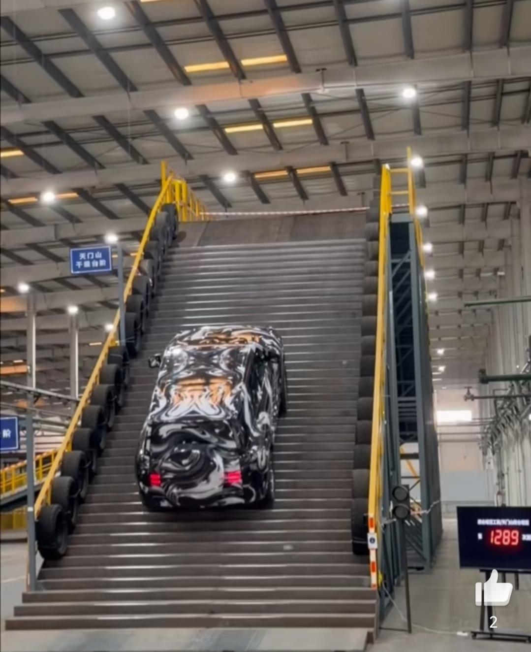 比亚迪把天梯搬进了厂房，这段内部爬坡演示，旁边牌子上标注“天门山”，当年路虎在天