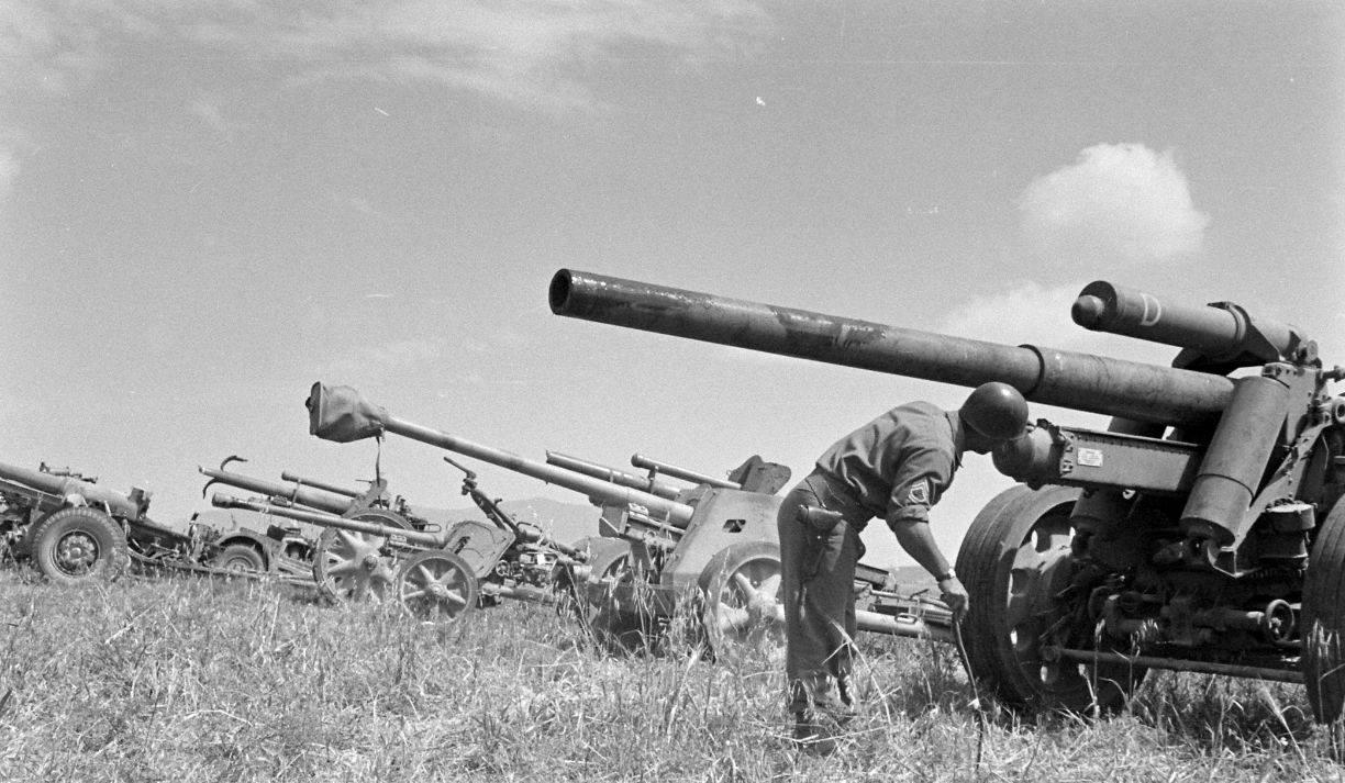 1943年，北非。一名美军技术士官正在检查一门缴获的德军150毫米重型野战榴弹炮