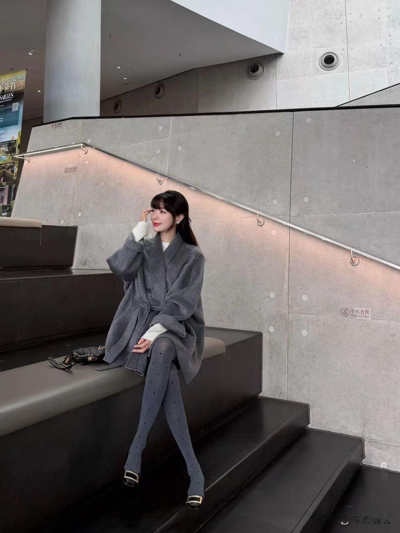 灰色大衣配灰波点袜，优雅温柔与灵动巧妙交织。灰色大衣，柔和似暮色轻纱，内搭白色，