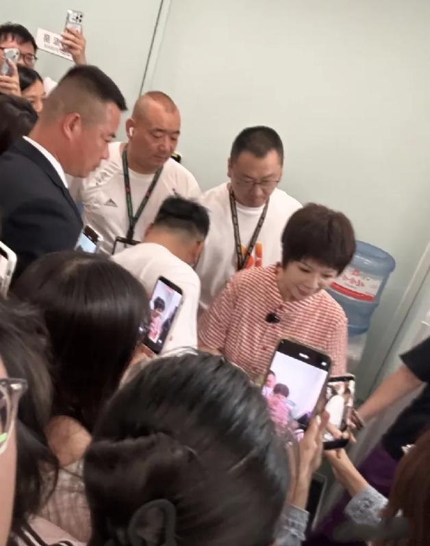 著名小品演员蔡明参观快手总部，她干练短发搭红白色格子长裙现身，脚趾甲还涂了紫红色