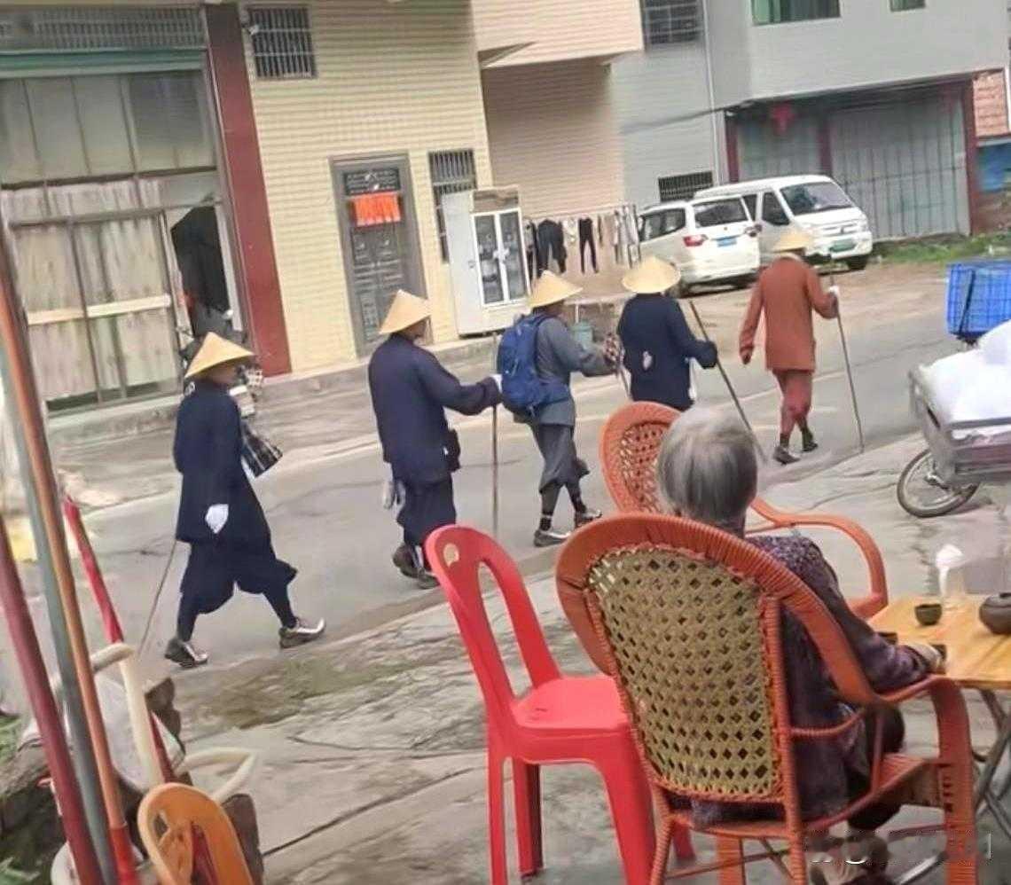 广东梅州，一队戴斗笠、持木棍、穿宽大怪鞋的人沉默赶路。路人看傻了眼。第一反应