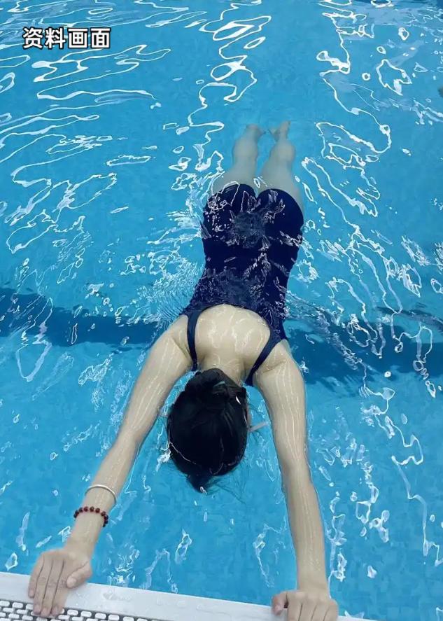 一名长相靓丽、身材出众的女子正常在泳池内游泳锻炼。女子身着泳衣在水中游动，水里水
