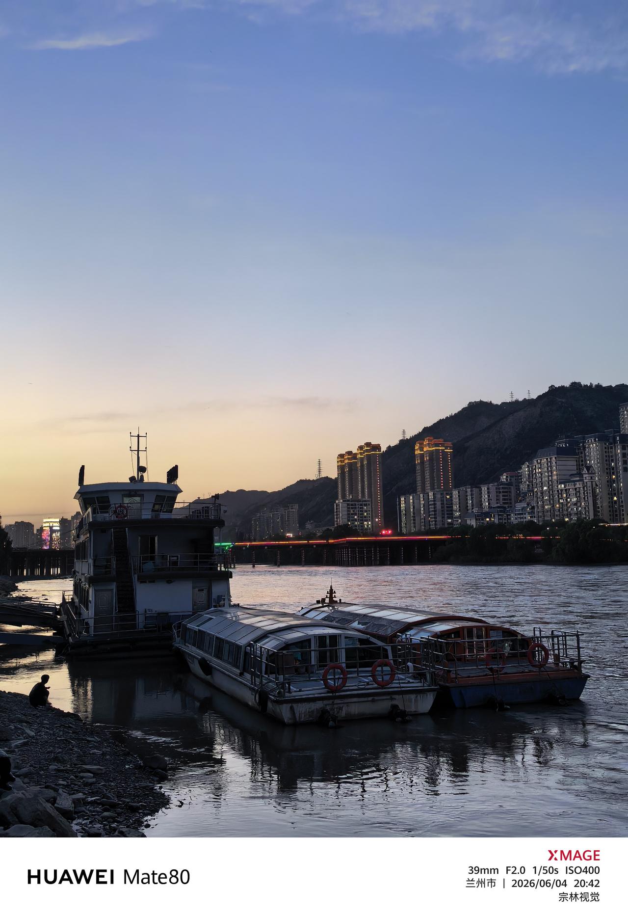 落日敛尽金辉，天色晕开浅蓝与柔橙的渐变。几艘游船静泊黄河浅岸，船身倚着粼粼静水，