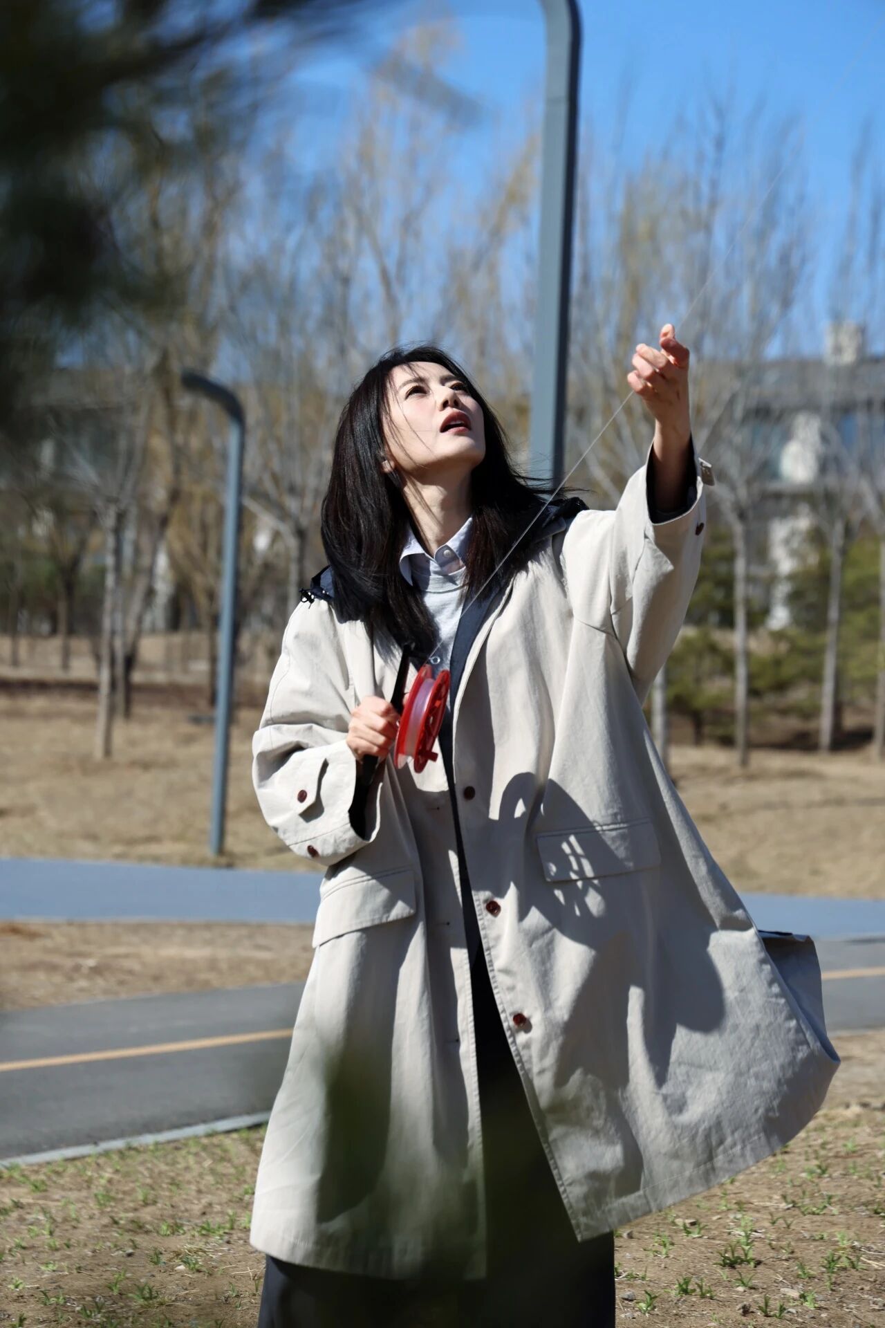高圆圆春风拂过郊野，风筝线牵起满格欢喜。身着浅卡其风衣，在晴日里整理线轴、举