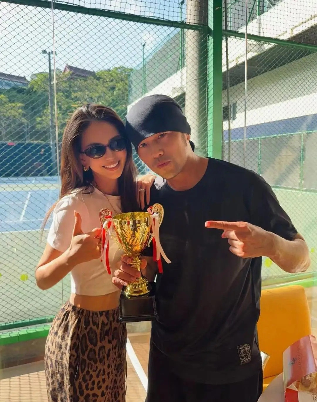 昆凌和老公周杰伦一起庆祝打网球比赛拿奖杯，她身穿超短小白衫配豹纹裤，露出性感的小