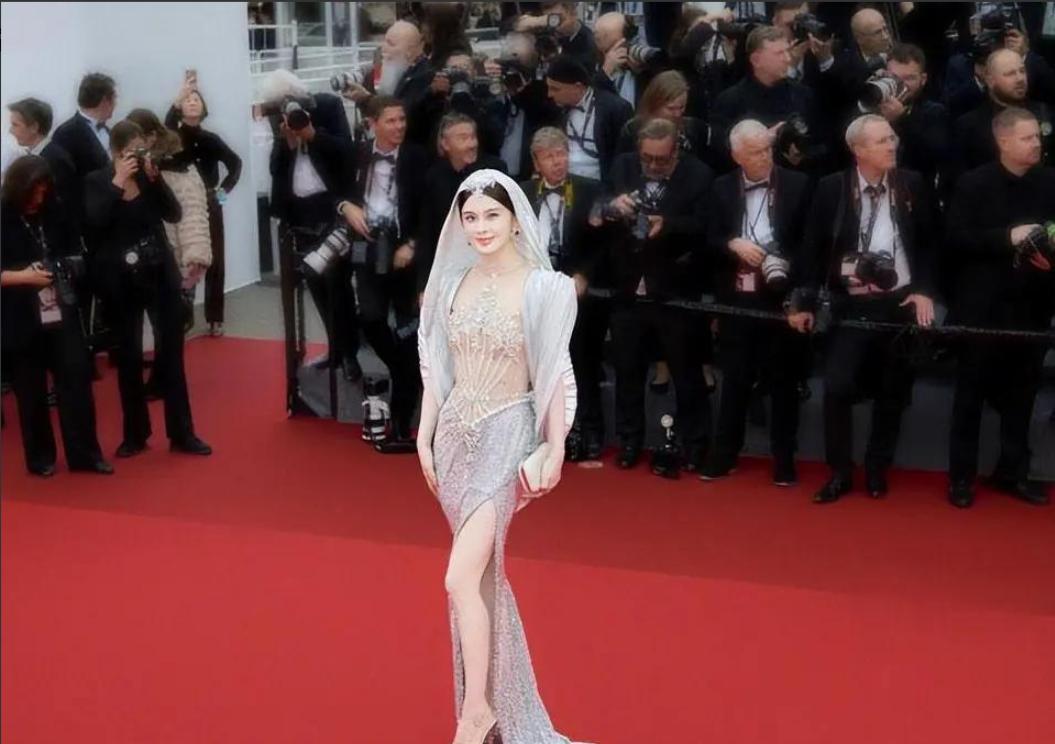 整整5分钟。就那么杵在戛纳的红毯台阶上，死活不走。身上那点薄纱，风一吹