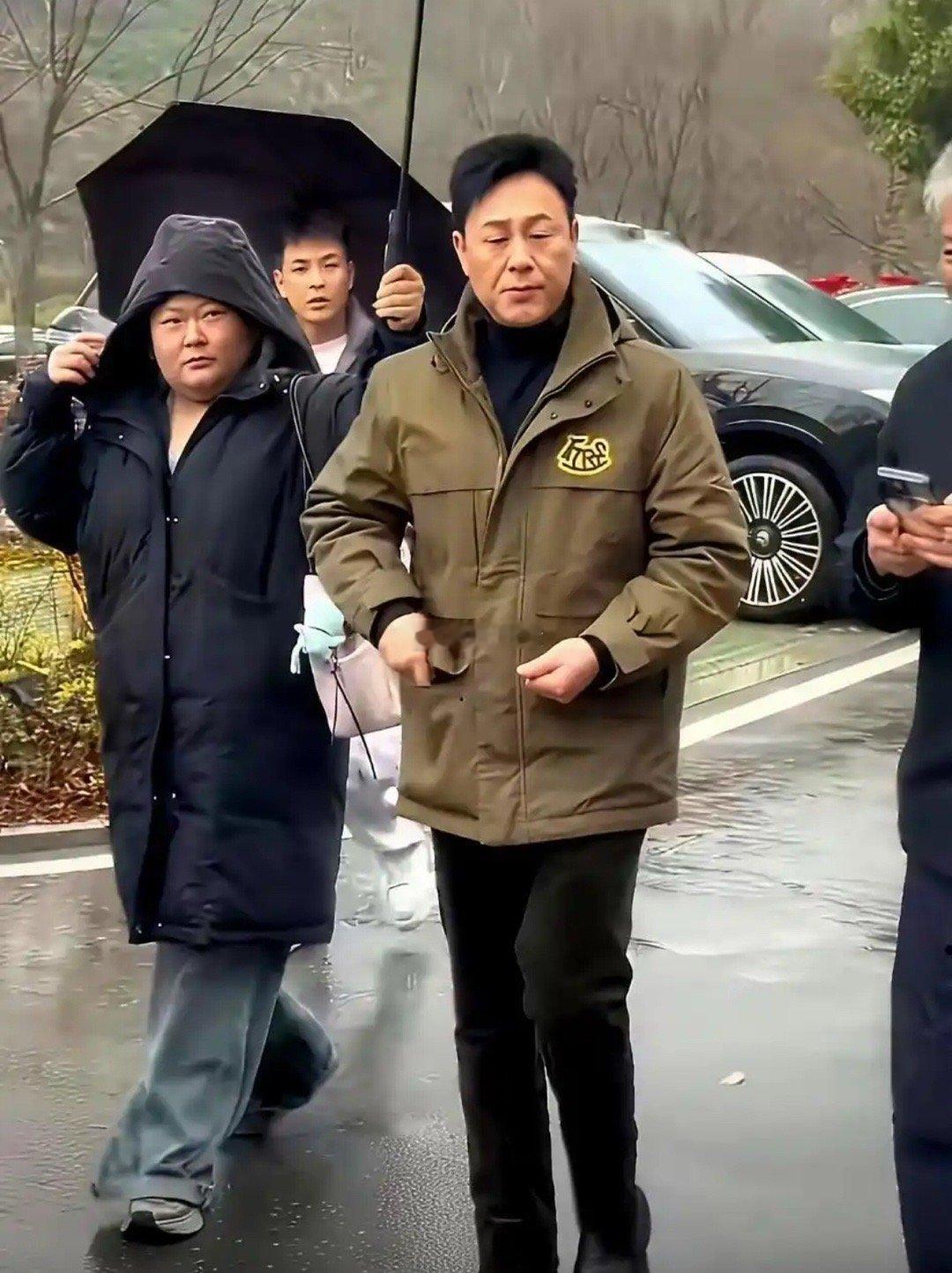 女助理半个身子淋着雨，张颂文却在伞下悠闲嗑瓜子。