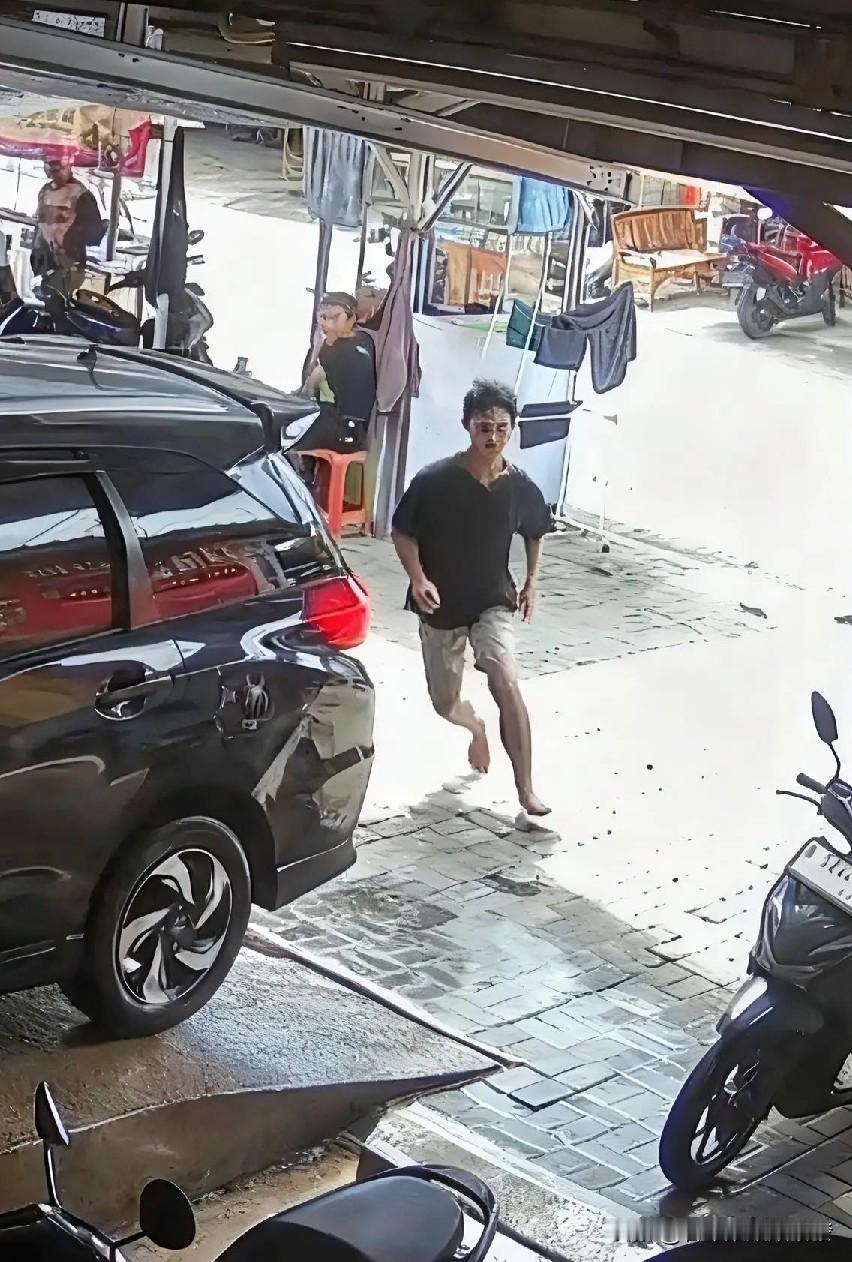 一辆正在修理的车突然后溜旁边正闲聊的修理工小哥看到后并没有去顶车阻止。