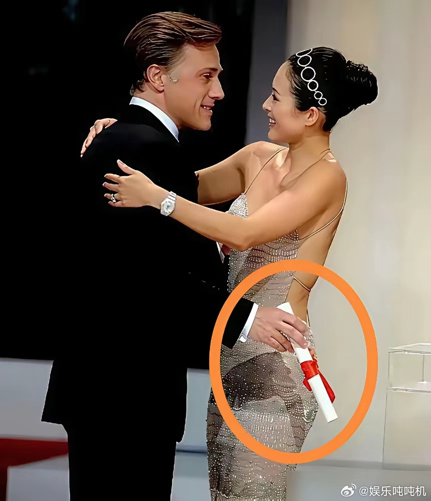 章子怡一个热情拥抱，竟被一只悬空手给婉拒了。红毯上，她一身露背礼服，笑得灿烂。主