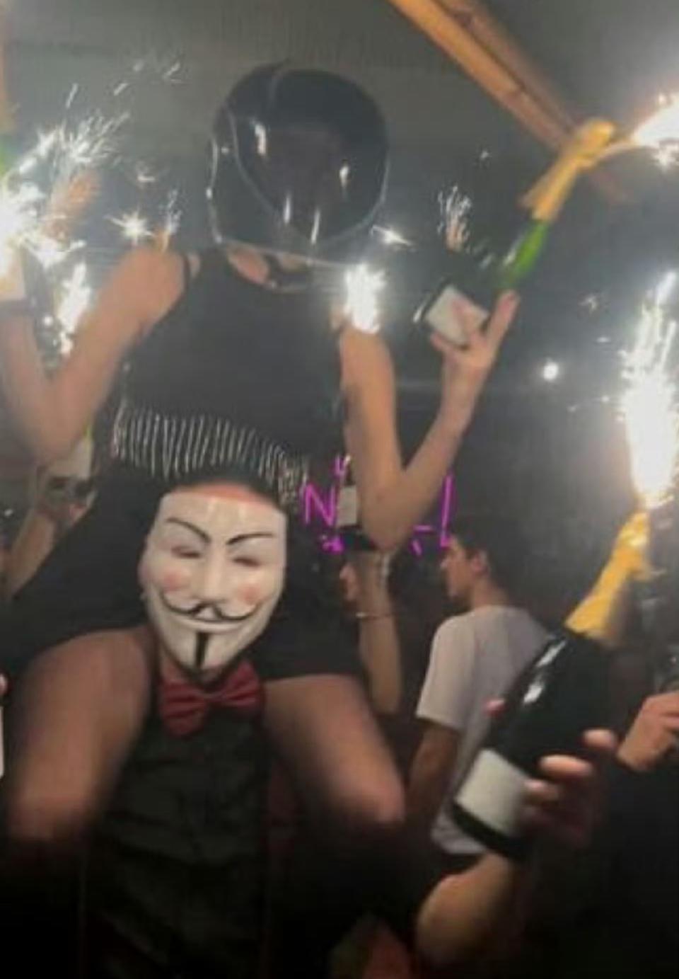 据说这就是瑞士酒吧纵火的凶手，戴面具的男子肩顶女子，女子一手拿着烟花，一手拿着香