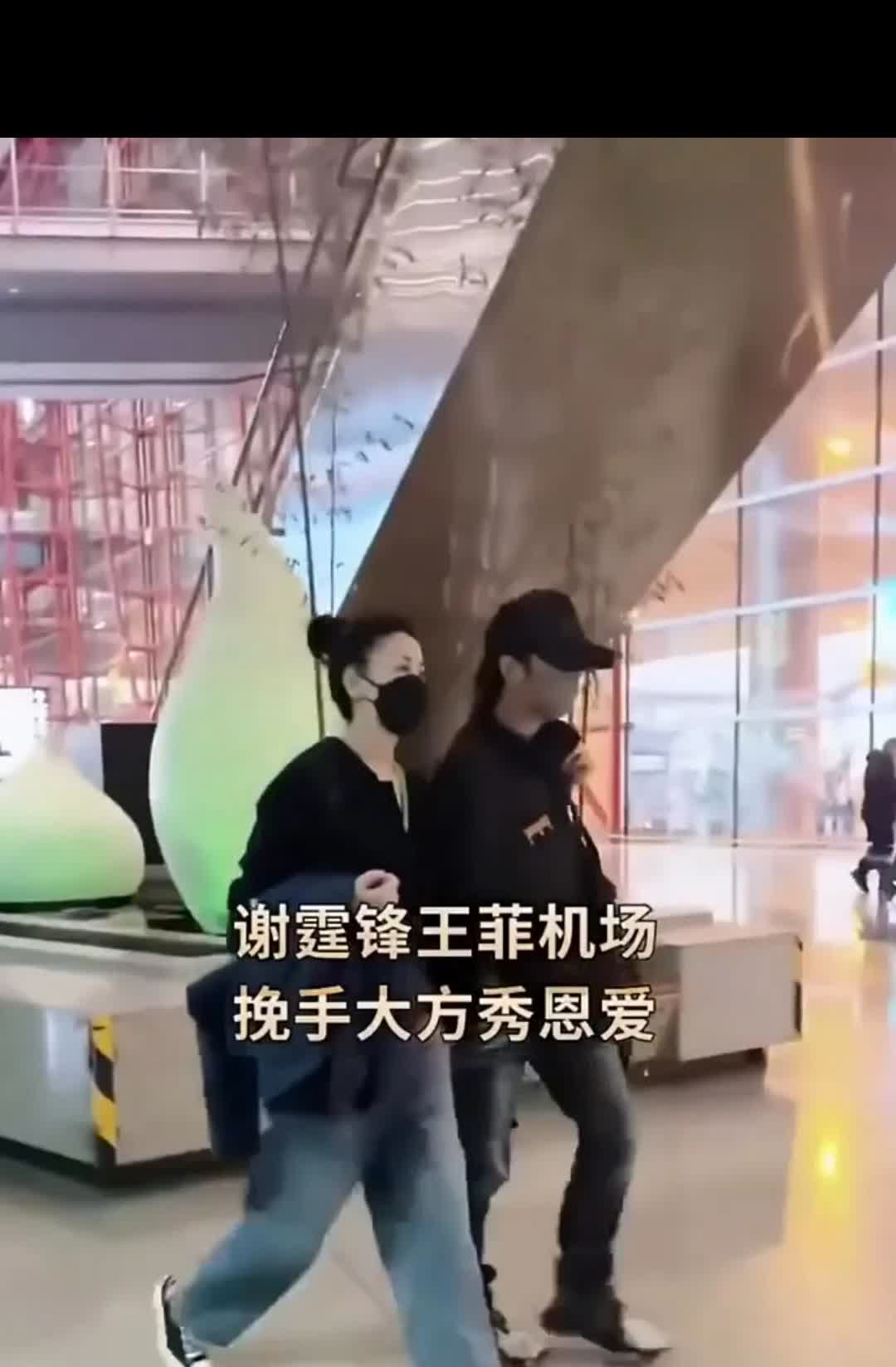 王菲谢霆锋机场亮相，挽着谢霆锋的手臂，王菲大大方方，谢霆锋一直低头走路，这两个人