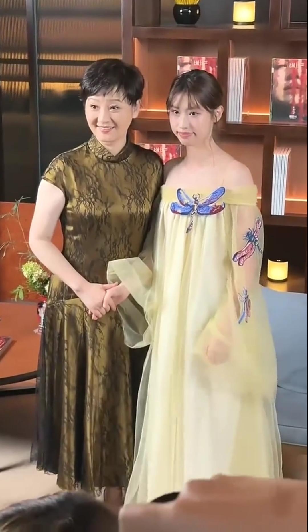 徐帆与养女徐朵在公开活动中的温馨瞬间，徐帆身穿一件暗金色中式改良旗袍裙，有东方典