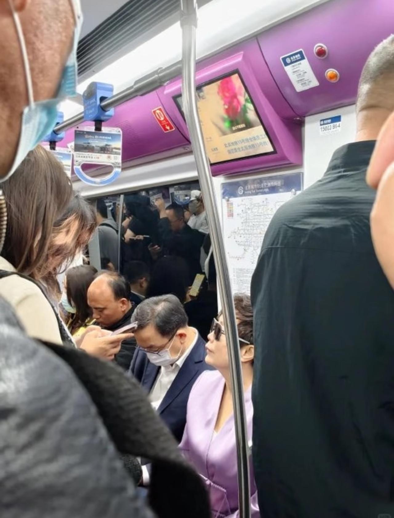 比亚迪创始人王传福带着妻子坐地铁出行，坐在座位上低着头摆弄手机，和普通大叔看上去