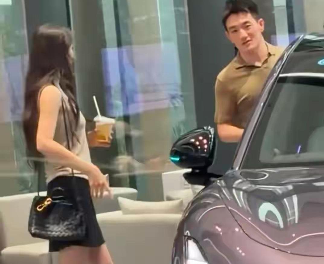 张馨予和何捷在广州看车，张馨予当天穿着灰色背心搭个黑短裙，手里还捧着杯奶茶，长发