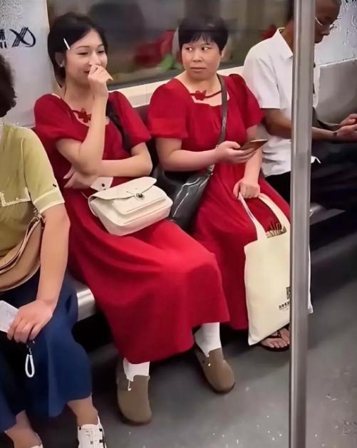 坐地铁偶然拍到暖心一幕，两位素不相识的乘客碰巧穿了同款红裙子挨着坐。年纪偏大的