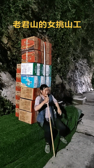 这位大妈是老君山风景区里的一名女性挑山工。虽然她身上背的货物都是泡面，但是背着