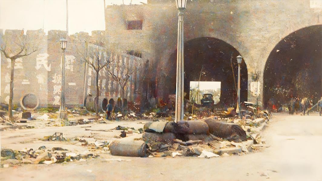 1937年，南京挹江门通往下关方向，城门洞下，一米多高的遇难者遗体与修筑路障的沙