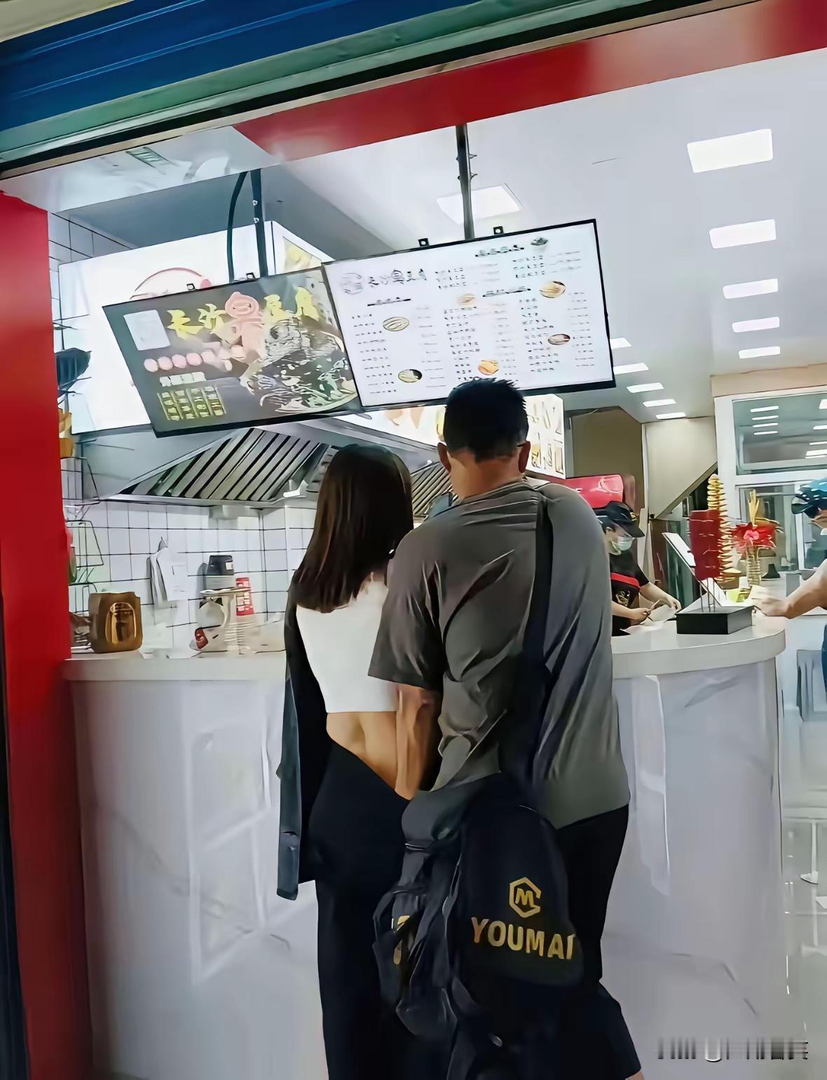 在“长沙臭豆腐”的小吃店前，本是热热闹闹品美食的场景，却因这对男女的亲密举止