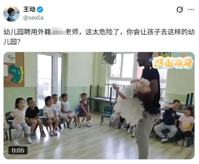一名黑人男性外教直接把身穿白色纱裙的小女孩横着抱在怀里，孩子整个人仰躺紧贴外教身