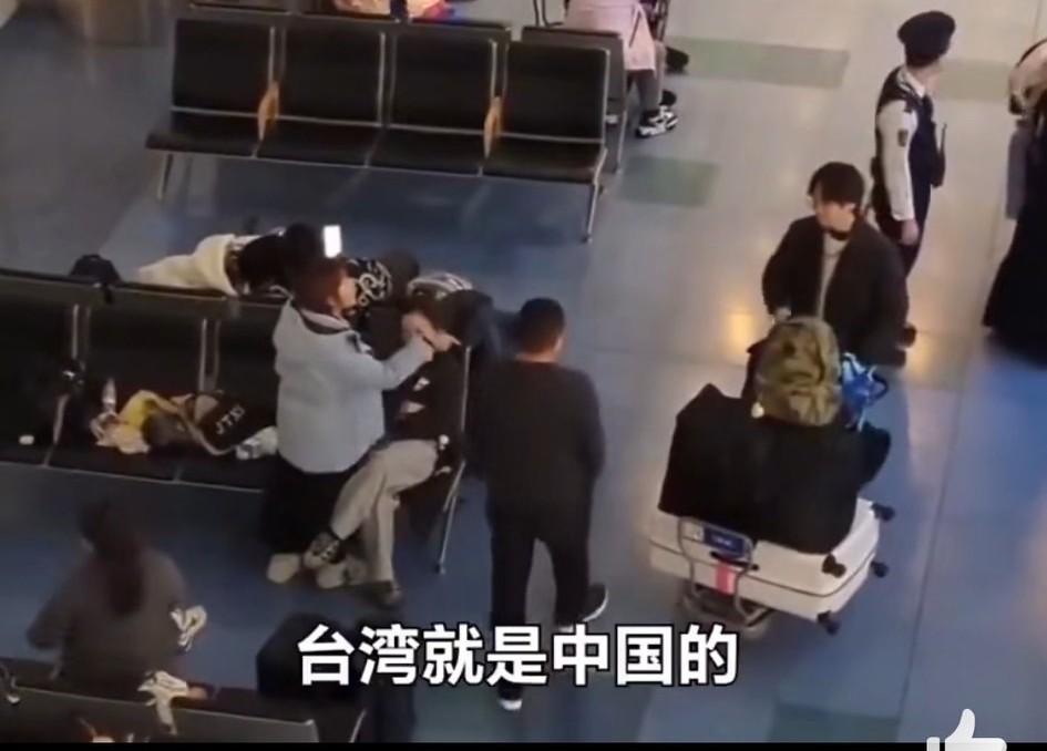 日本羽田机场内，推着一大车行李箱的男子是台湾游客，他指责边上一群大陆游客大量占座