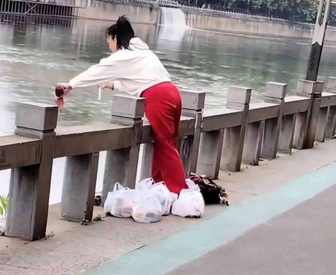 女子带着几袋子的饮品往河里倒是什么操作？有人说她是在“放生”因为听到女子嘴里