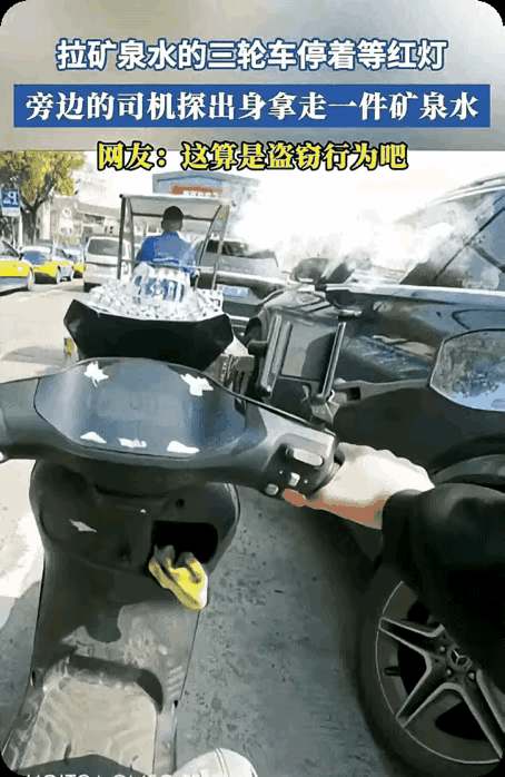 拉矿泉水的三轮车在等红灯，旁边的司机探出身来拿走一件矿泉水。网友：这算是盗窃行为