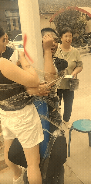 这不是新郎和新娘。发视频的人说，这是家里生了女孩过百宴，绑在电线杆子上的俩人，