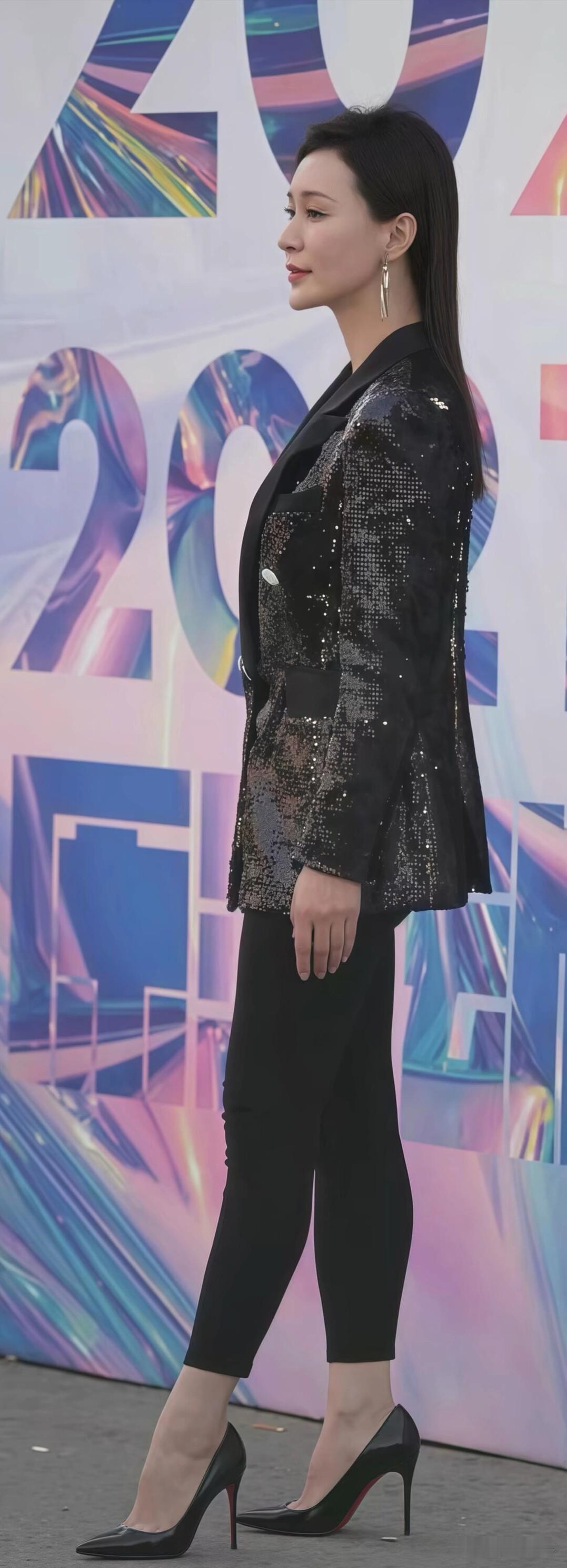 黑色亮片西装搭配黑色裤子，简约又有亮点。脚踩黑色高跟鞋，整体造型利落大方，很有气