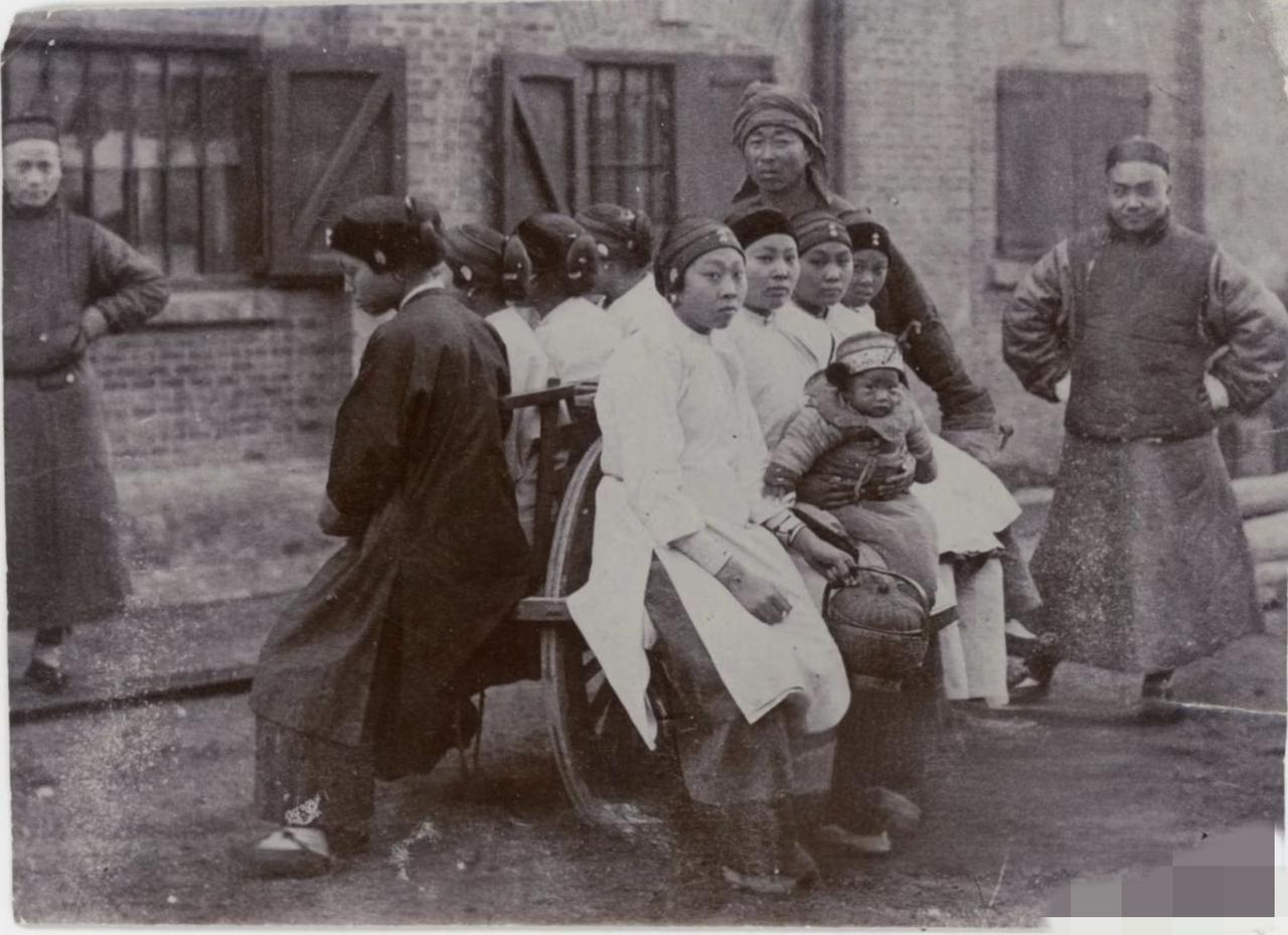 这是一张晚清时期，上海的老照片，一个车夫用独轮车推起八个女子和一个小孩子。但是