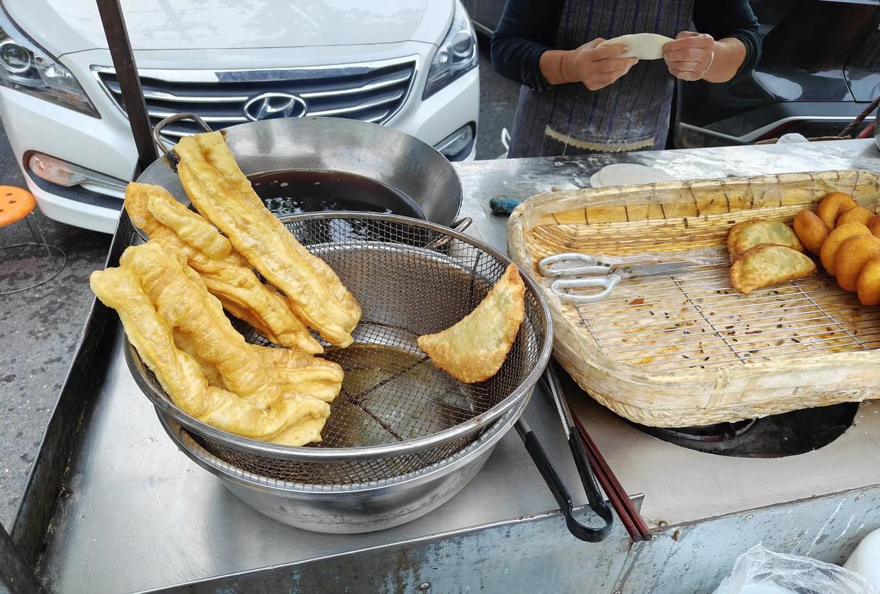 我每天都会路过这个街口。炸油条的大妈，总是下午5点出现在这里。我经常拐去买她