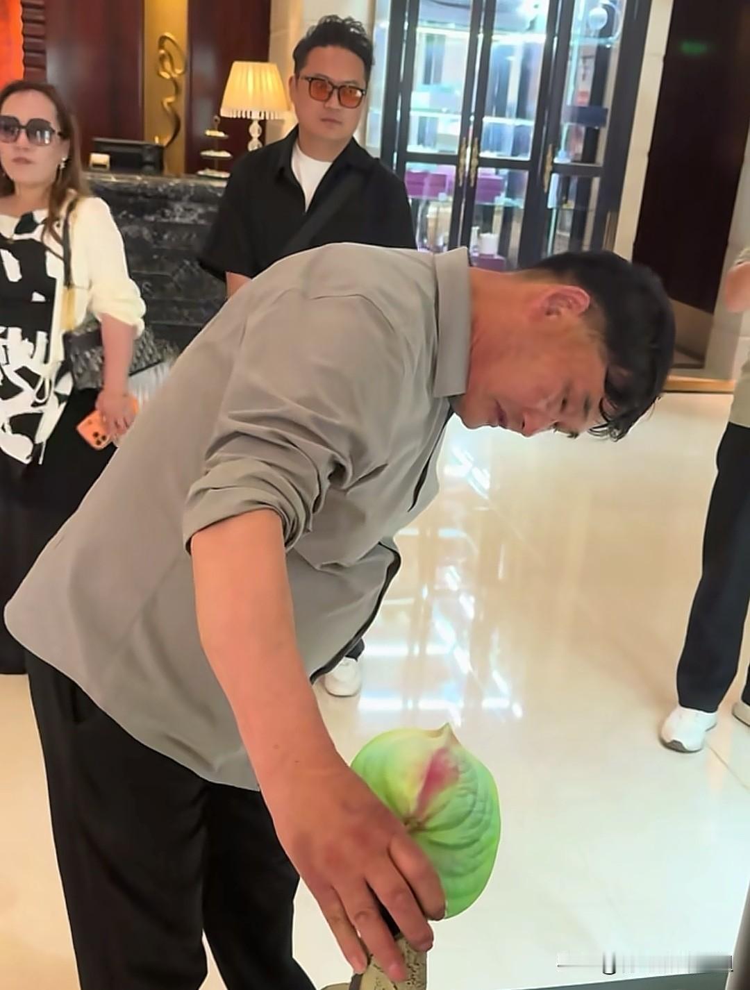 大衣哥驻足品鉴艺术摆件，俯身细看满眼好奇。农民歌手朱之文现身一处室内场所，被一
