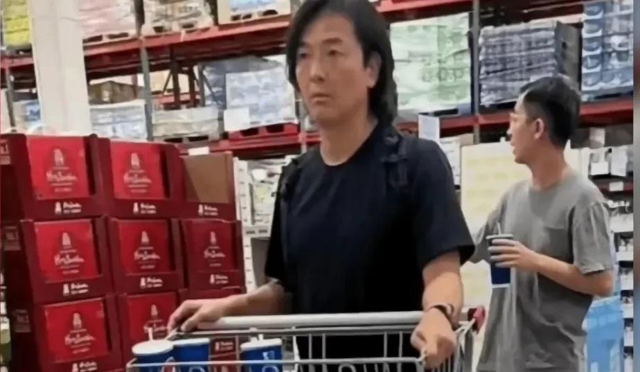 郑伊健夫妻俩现身日本福冈，画面中的郑伊健肤色有点黑，留着长发，脸发福不少，流畅的
