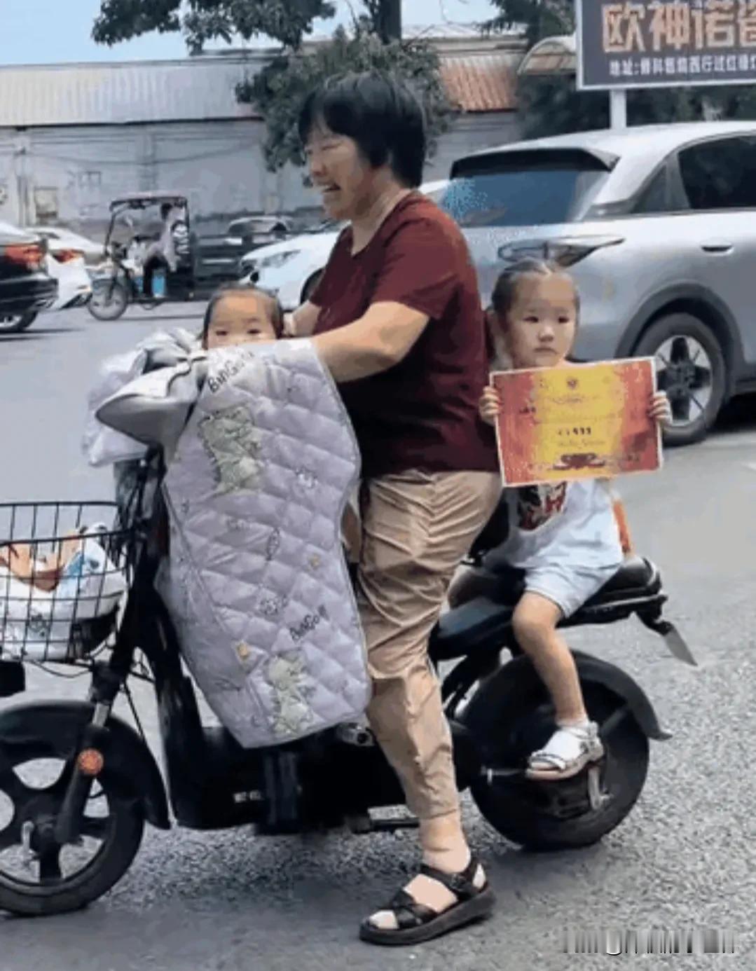 这下全国人民都知道了！这个小女孩，坐在奶奶电动车座后，一路举着她在学校刚获得