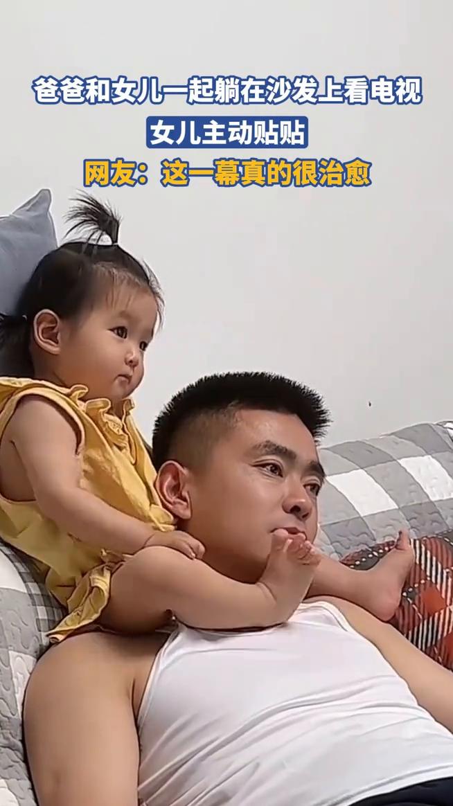 爸爸和女儿一起躺在沙发上看电视，女儿主动贴贴。网友：这一幕真的很治愈。