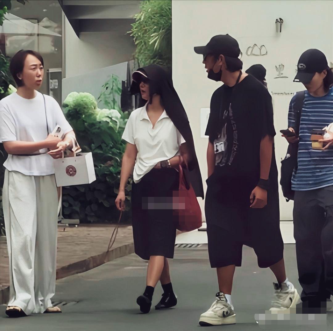 路人镜头下的周迅陈坤同框散步画面，周迅白色体恤，配黑色五分中裤，将黑色外套直接罩