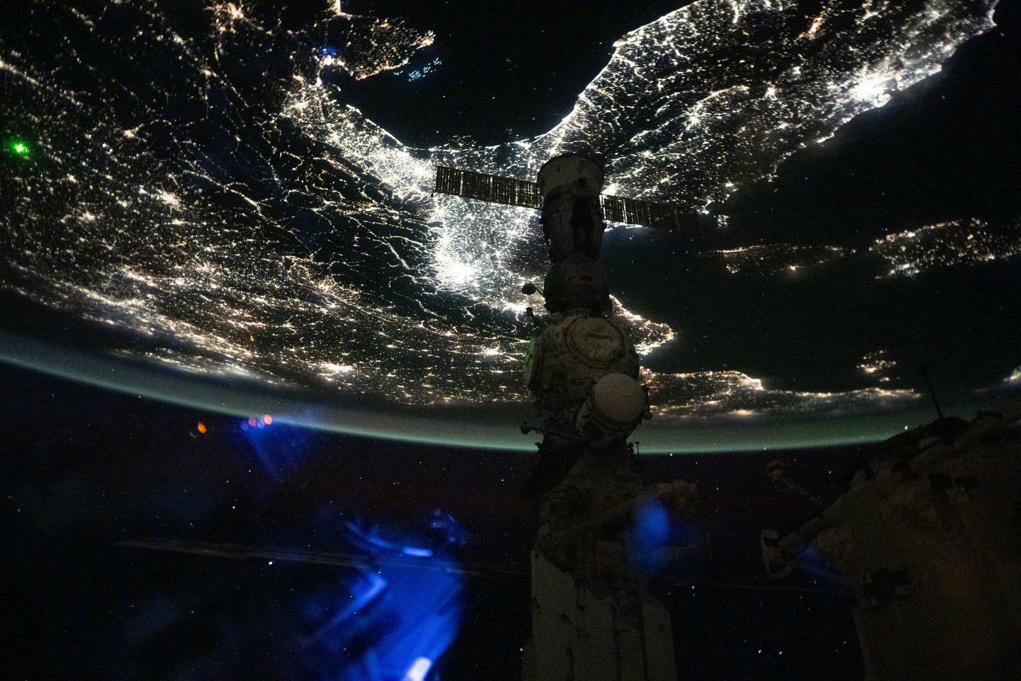 从轨道上方俯瞰地球，极光翩翩起舞，城市灯火闪耀闪烁，气辉为天空涂抹出绚丽色彩。这