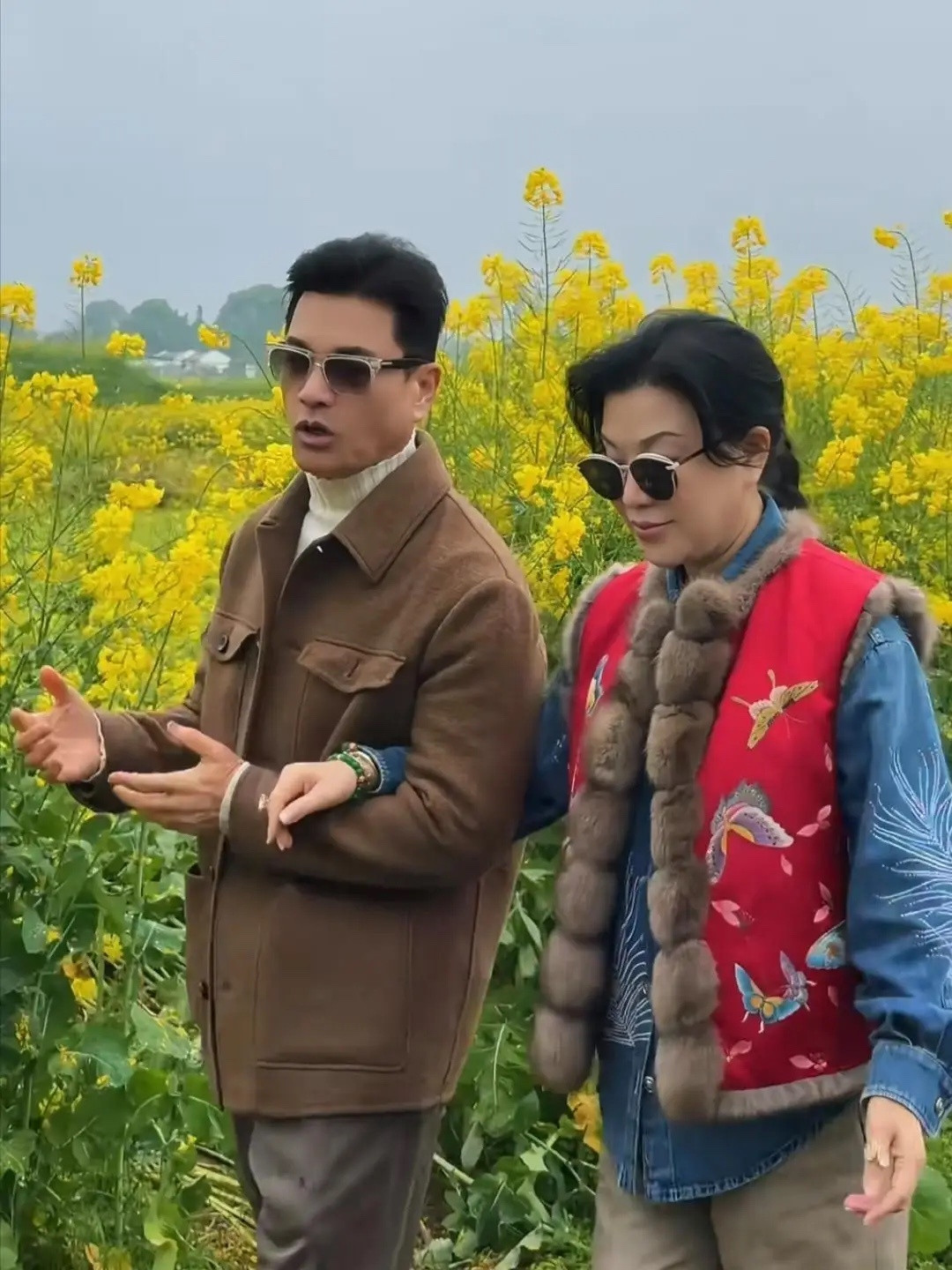 70岁吕良伟和老婆杨小娟到农村乡下看油菜花，夫妻俩挽手走在田间的泥泞小路上，他们